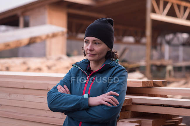 Задумчивая женщина, стоящая со скрещенными руками на деревянной доске — стоковое фото
