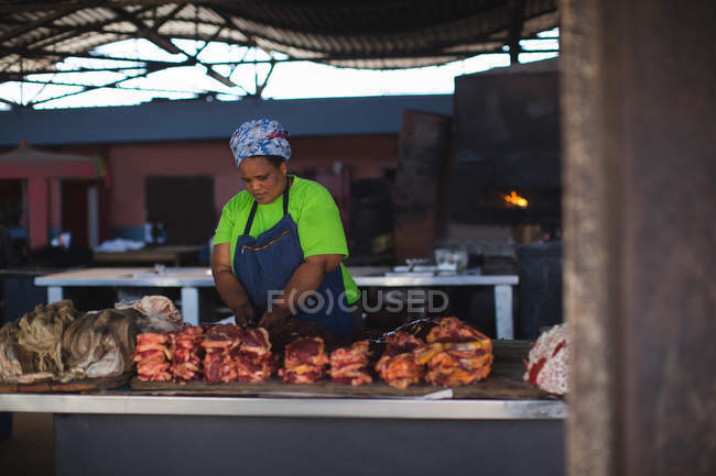 Female butcher standing at meat shop — Stock Photo