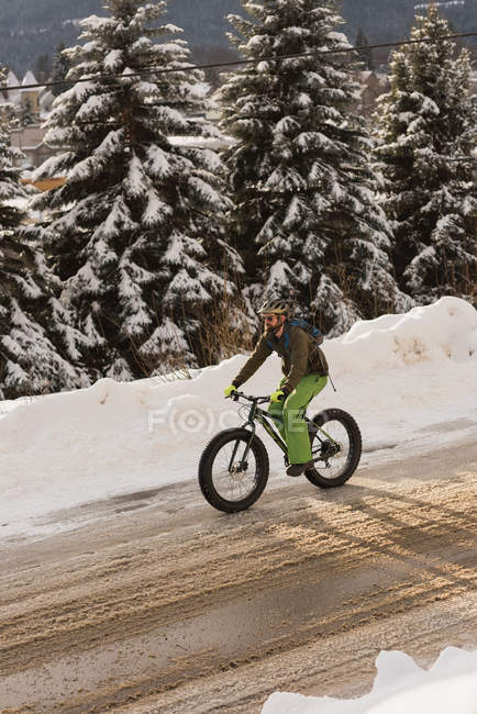 Homem andando de bicicleta na rua durante o inverno — Fotografia de Stock