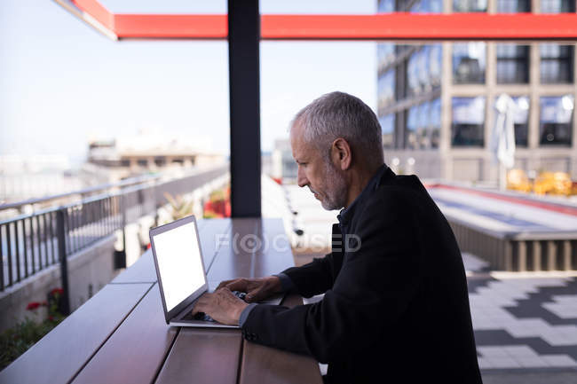 Businessman using laptop in hotel premises — Stock Photo