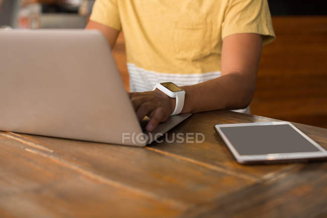Средняя секция человека использует ноутбук в кафетерии — стоковое фото