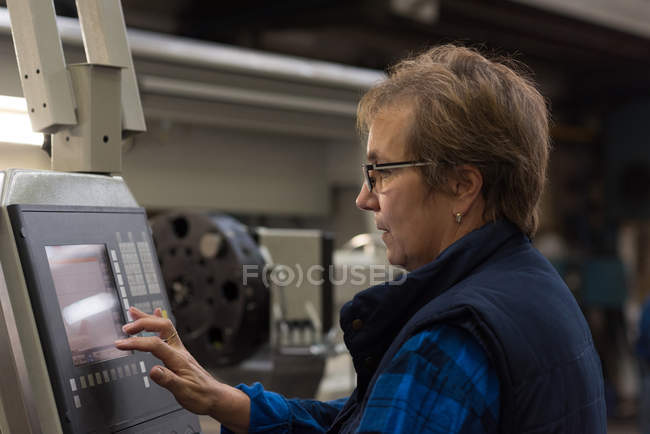 Female technician operating machine in metal industry — Stock Photo