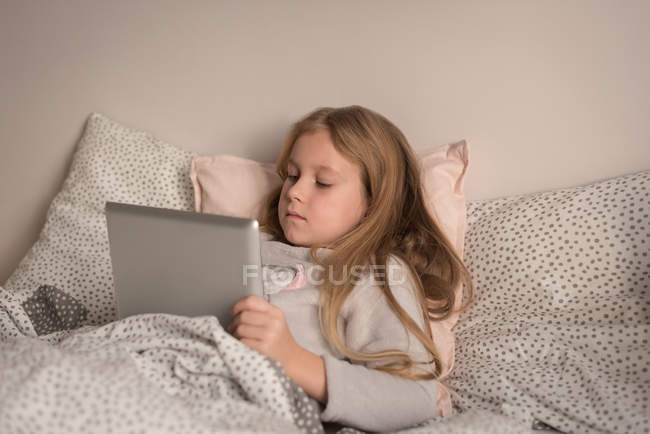 Девушка, использующая цифровой планшет в спальне дома — стоковое фото