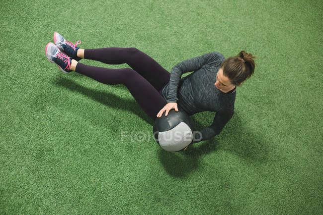 Donna che pratica stretching con una palla sul tappeto erboso — Foto stock