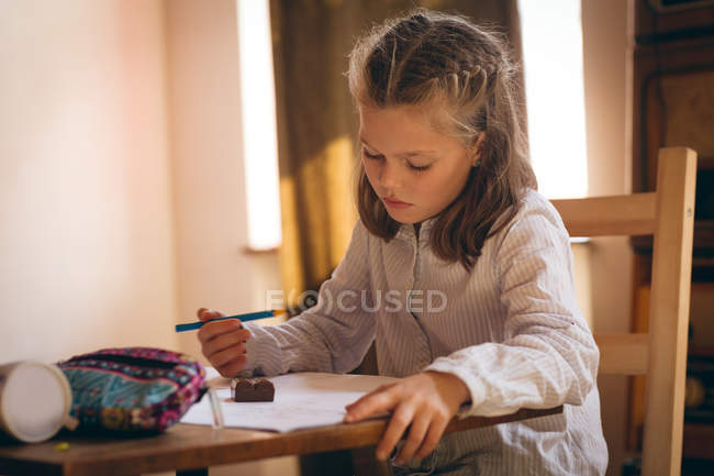 Menina atenta fazendo seu dever de casa em casa — Fotografia de Stock