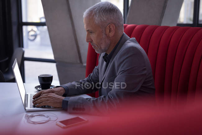 Uomo d'affari che utilizza il computer portatile nella hall dell'hotel — Foto stock