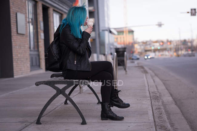 Mujer con estilo tomando helado en la calle de la ciudad - foto de stock