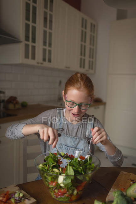 Girl preparing vegetable salad in kitchen at home — Stock Photo