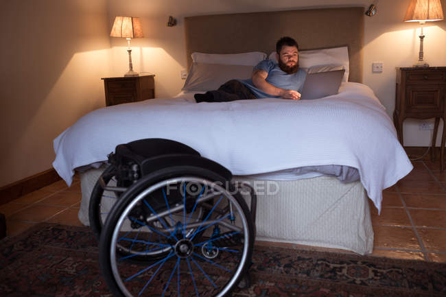 Homem com deficiência usando laptop no quarto em casa — Fotografia de Stock