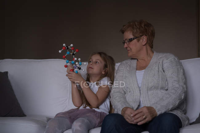 Бабушка и внучка играют с молекулярной моделью в гостиной дома — стоковое фото