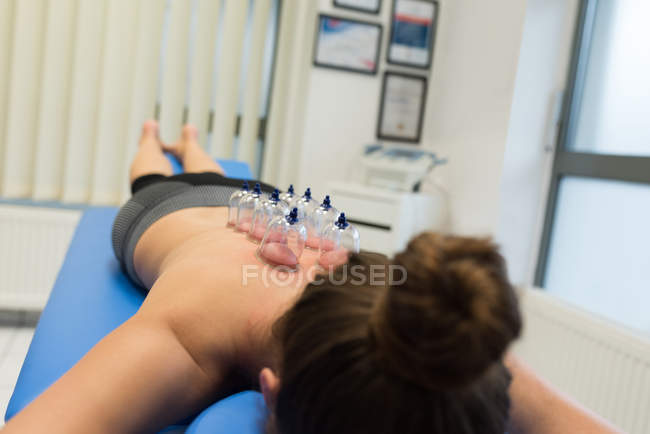 Woman lying on chest with cupping therapy on back in clinic — Stock Photo