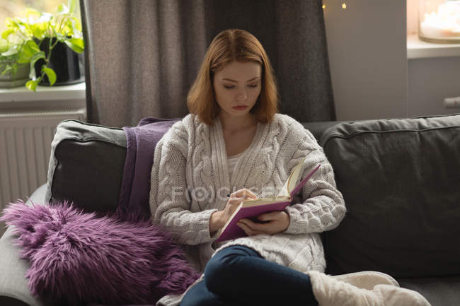 Frau schreibt zu Hause im Wohnzimmer an Tagebuch — Stockfoto