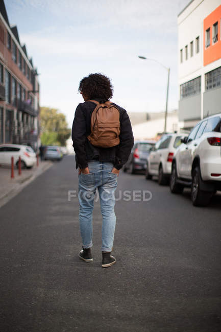 Вид сзади на человека, идущего по городской улице с руками в кармане — стоковое фото
