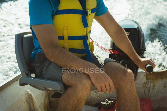 Mid section of man travelling in motorboat on a lake — Stock Photo