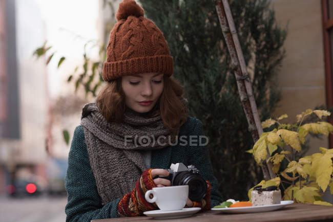 Женщина рассматривает фото на камеру в кафе на открытом воздухе — стоковое фото