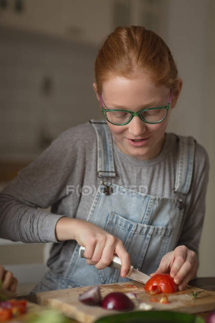 Chica cortar verduras en la cocina en casa - foto de stock