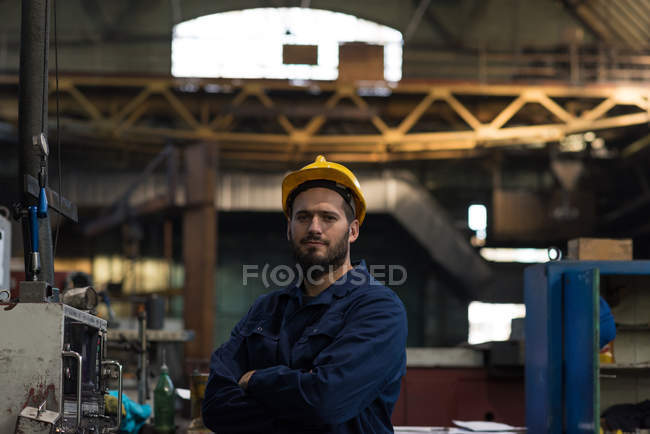 Ritratto di tecnico sicuro in piedi con le braccia incrociate nell'industria metallurgica — Foto stock