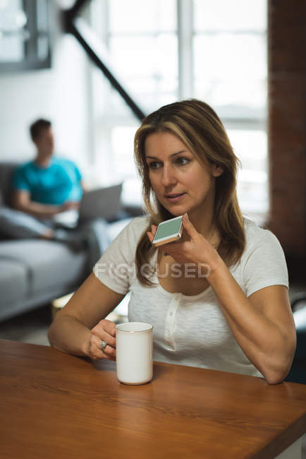 Donna che parla al cellulare in salotto a casa — Foto stock