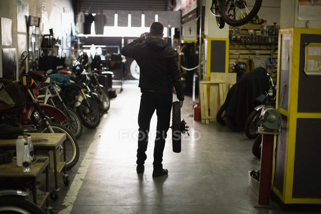 Rückansicht des Mechanikers, der Reifen in der Garage hält — Stockfoto
