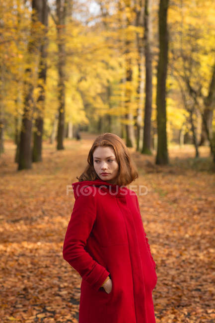 Donna in piedi con la mano in tasca al parco durante l'autunno — Foto stock