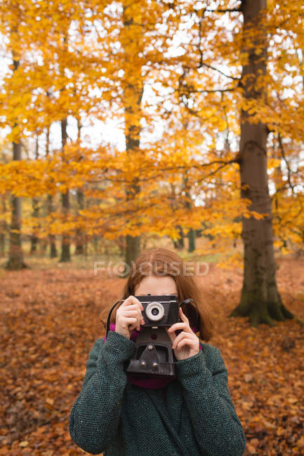 Donna scattare foto con fotocamera vintage nel parco durante l'autunno — Foto stock