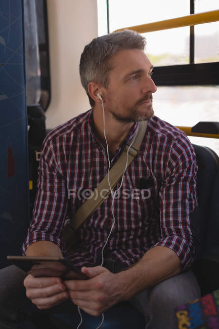 Uomo che ascolta musica su tablet digitale mentre viaggia in tram — Foto stock