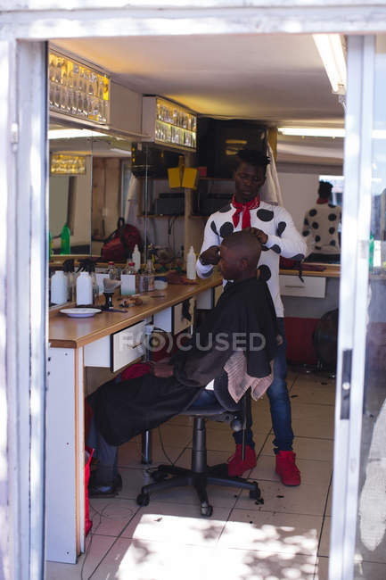 Barbiere taglio capelli cliente in negozio di barbiere — Foto stock
