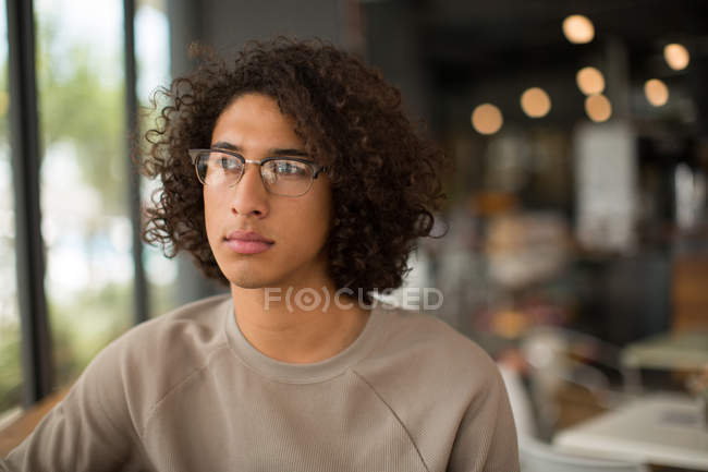 Jovem homem pensativo sentado na cafetaria — Fotografia de Stock