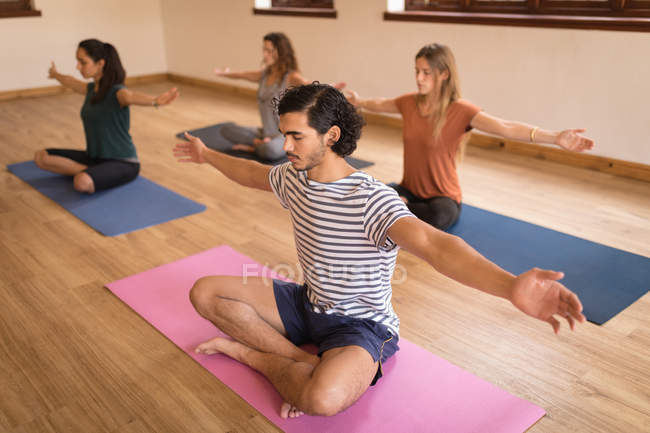Grupo de personas que realizan ejercicio de yoga juntos en el gimnasio - foto de stock