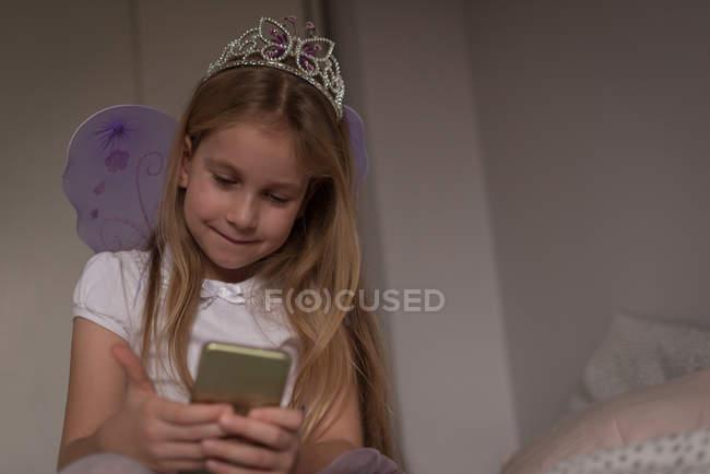 Fille en utilisant téléphone portable dans la chambre à coucher à la maison — Photo de stock