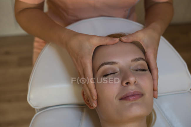 Estetista dando massaggio viso al cliente femminile in salotto — Foto stock