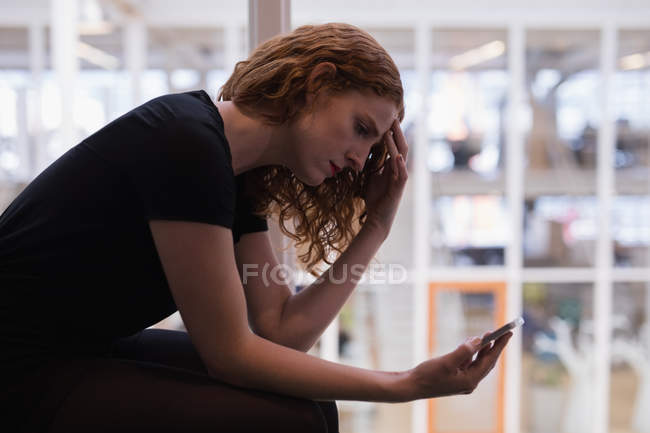 Женщина графический дизайнер с помощью мобильного телефона в офисе — стоковое фото