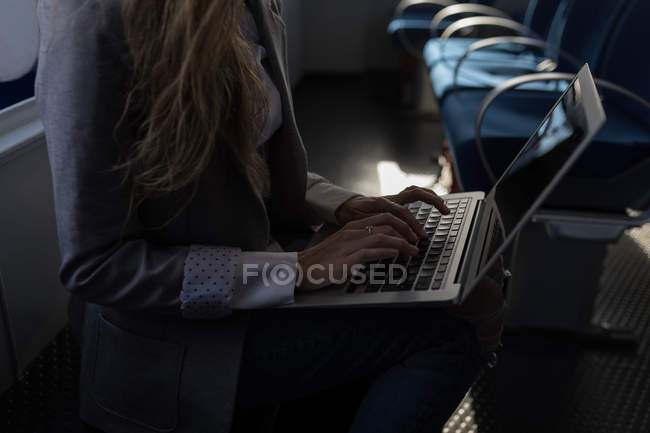 Partie médiane de la femme utilisant un ordinateur portable dans un bateau de croisière — Photo de stock