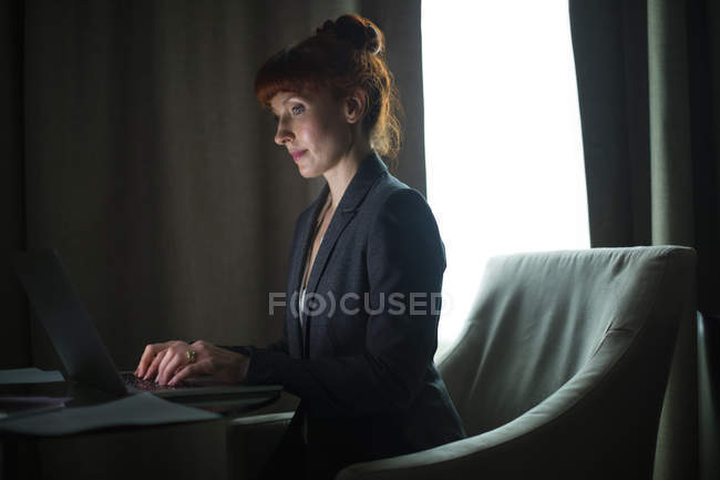 Donna d'affari che utilizza il computer portatile in camera d'albergo — Foto stock