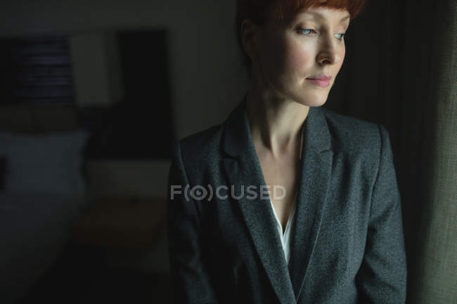 Nachdenkliche Geschäftsfrau steht im Hotelzimmer — Stockfoto
