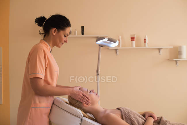 Beautician giving face massage to female customer at parlour — Stock Photo