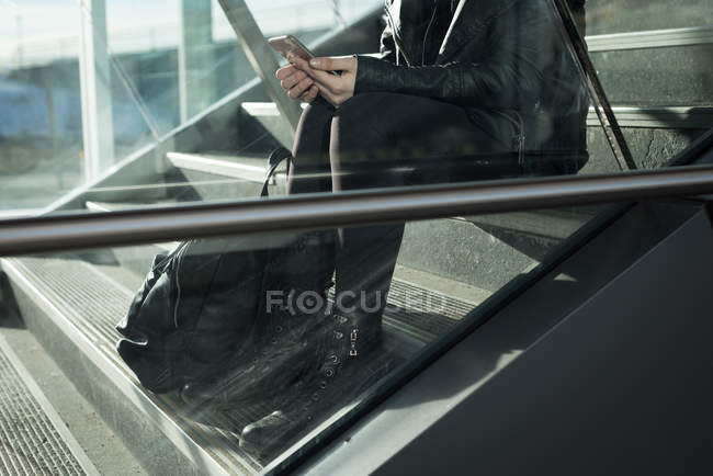 Низька частина жінки, використовуючи мобільний телефон на сходах — стокове фото