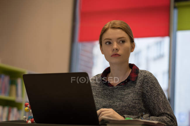 Молодая женщина с ноутбуком в библиотеке — стоковое фото