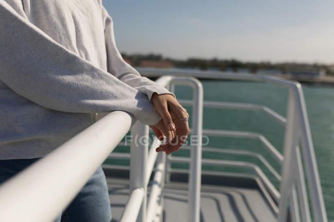 Mid section of woman standing near railings of cruise ship — Stock Photo