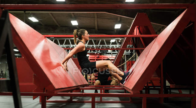 Muskulöse Frau übt Liegestütze an schiefer Wand im Fitnessstudio — Stockfoto