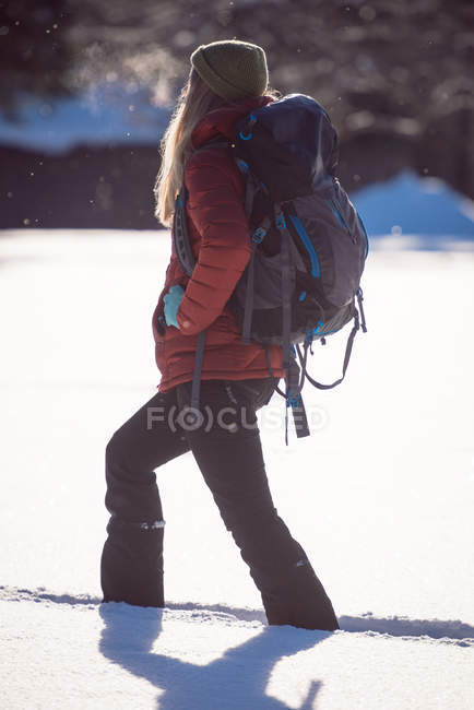 Femme marchant sur un paysage enneigé par une journée ensoleillée — Photo de stock