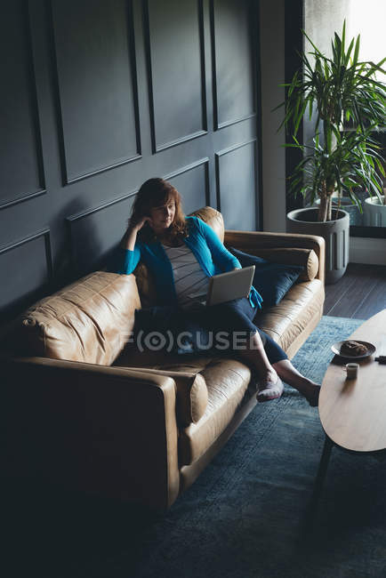 Businesswoman using laptop on a sofa in office — Stock Photo