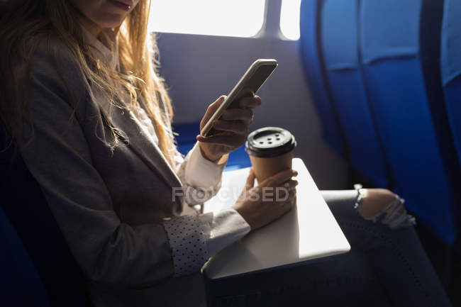 Media sezione di donna che utilizza il telefono cellulare mentre prende il caffè in nave da crociera — Foto stock