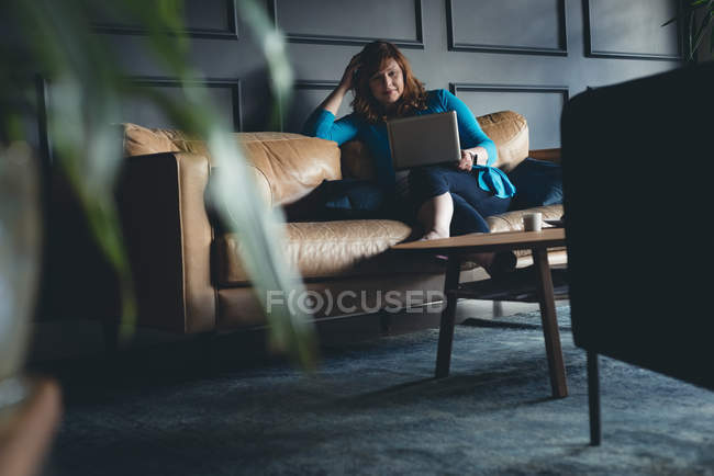 Бизнесмен, использующая ноутбук на диване в офисе — стоковое фото