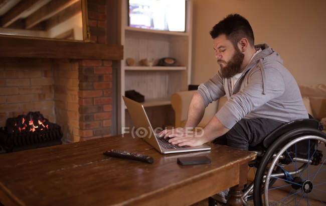 Disabled young man using laptop at home — Stock Photo