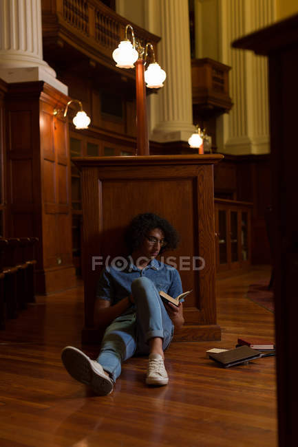 Молодий чоловік читає книгу в бібліотеці — стокове фото