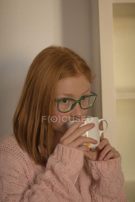 Задумчивая девушка пьет кофе дома — стоковое фото