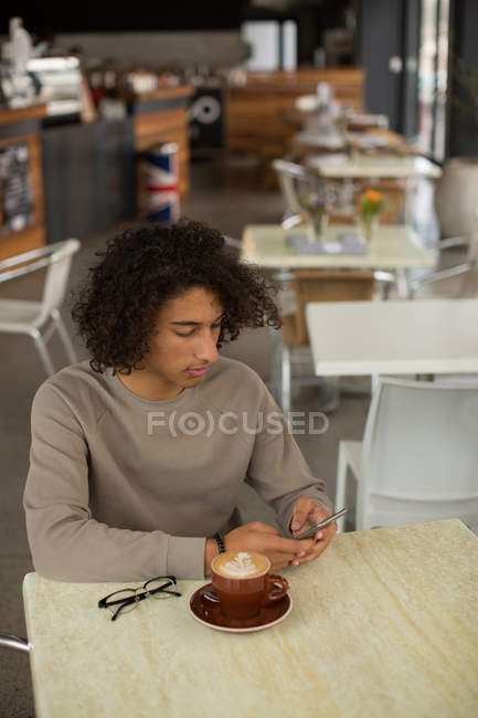 Молодий чоловік використовує мобільний телефон в ресторані — стокове фото