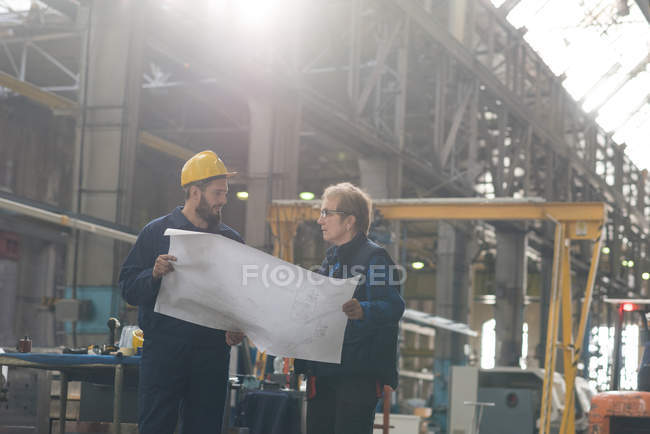 Techniker diskutiert Bauplan mit seinem Kollegen in der Metallindustrie — Stockfoto