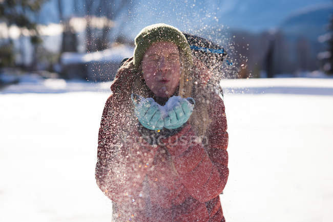 Красива жінка дме сніг з її рук взимку — стокове фото